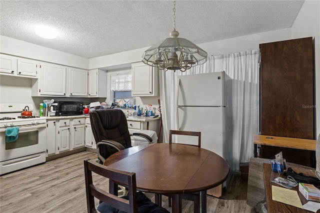 kitchen featuring light wood-type flooring, white appliances, decorative light fixtures, and white cabinetry