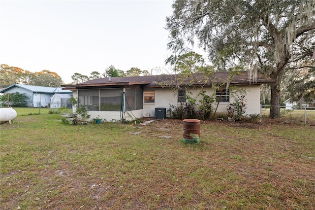 back of house with central air condition unit, a sunroom, and a yard