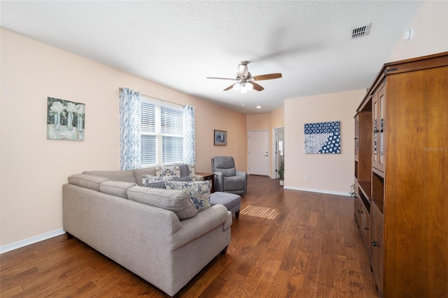 living room with a textured ceiling, ceiling fan, and dark wood-type flooring