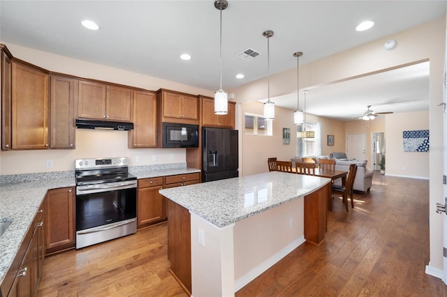 kitchen featuring ceiling fan, black appliances, pendant lighting, hardwood / wood-style flooring, and a center island