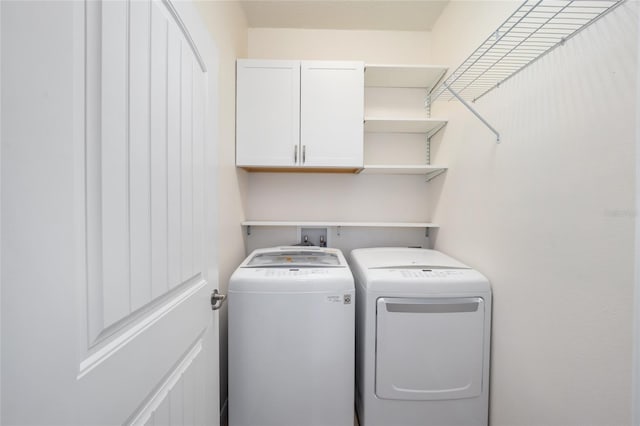 clothes washing area featuring washer and clothes dryer and cabinets