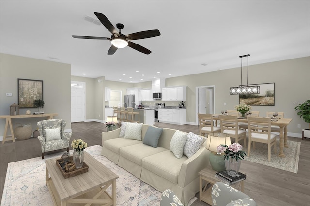 living room featuring ceiling fan with notable chandelier and hardwood / wood-style flooring