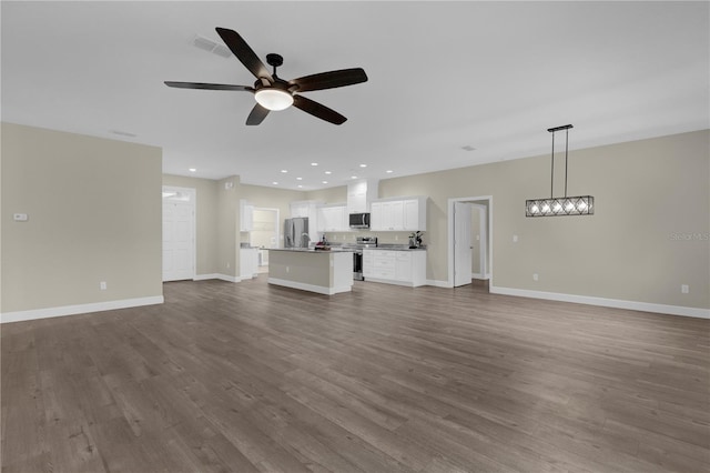 unfurnished living room featuring ceiling fan and hardwood / wood-style flooring