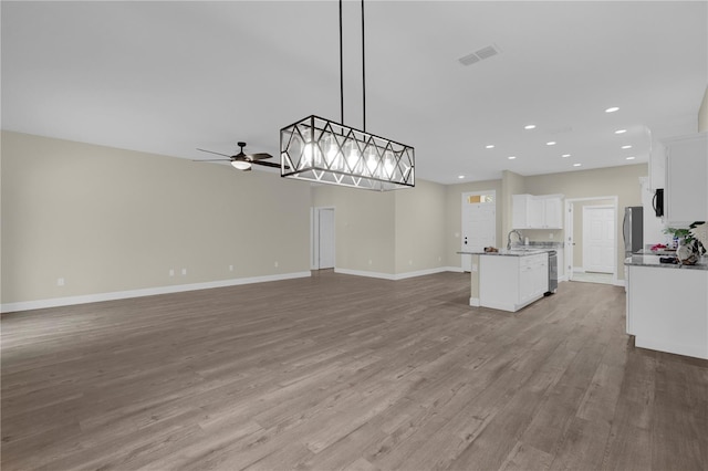 unfurnished living room with light hardwood / wood-style floors, ceiling fan, and sink