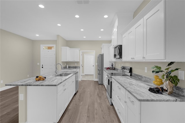 kitchen with appliances with stainless steel finishes, light stone counters, sink, light hardwood / wood-style flooring, and white cabinetry