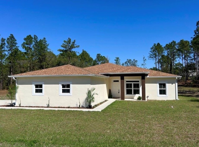 view of front of home with a shingled roof, a front yard, and stucco siding