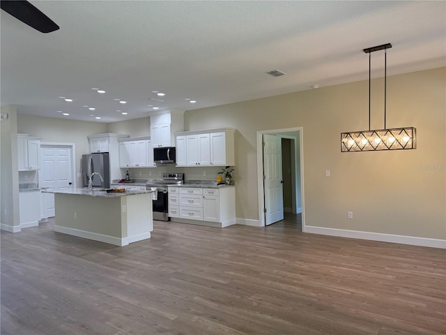 12205 SW 71st Lane Rd, Ocala, FL 34481 - kitchen featuring stainless steel appliances, white cabinets, wood finished floors, recessed lighting, and an island with sink