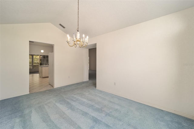 carpeted empty room featuring a chandelier and vaulted ceiling