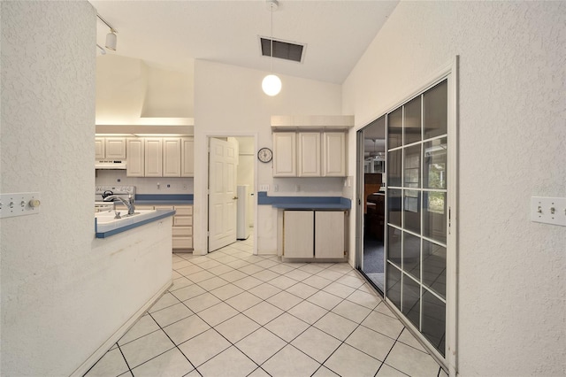 kitchen featuring pendant lighting, high vaulted ceiling, cream cabinets, sink, and light tile patterned floors