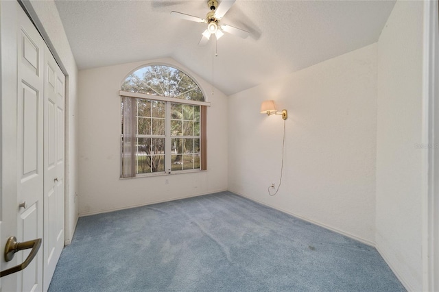 unfurnished bedroom featuring carpet flooring, a textured ceiling, ceiling fan, a closet, and lofted ceiling