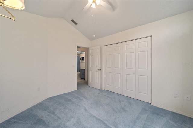 unfurnished bedroom featuring ceiling fan, a closet, light colored carpet, and lofted ceiling