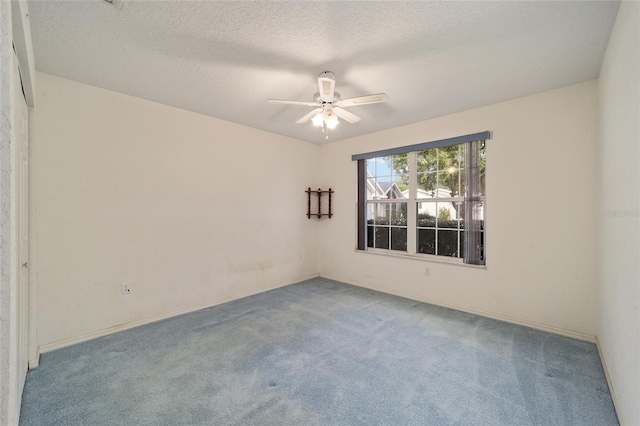 spare room featuring ceiling fan, light colored carpet, and a textured ceiling