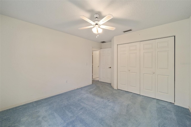 unfurnished bedroom featuring ceiling fan, a closet, carpet floors, and a textured ceiling