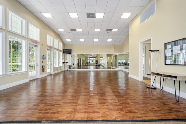 workout room featuring hardwood / wood-style floors, a paneled ceiling, and a high ceiling