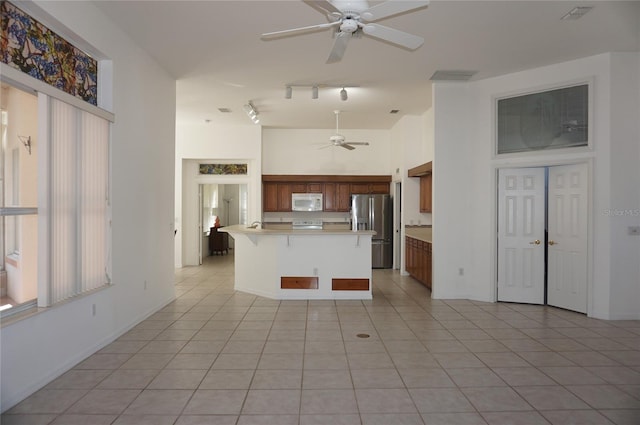 kitchen with stainless steel fridge, a kitchen breakfast bar, ceiling fan, and light tile patterned flooring