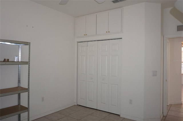 unfurnished bedroom with ceiling fan, a closet, and light tile patterned floors