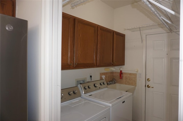 laundry room with sink, washing machine and dryer, and cabinets