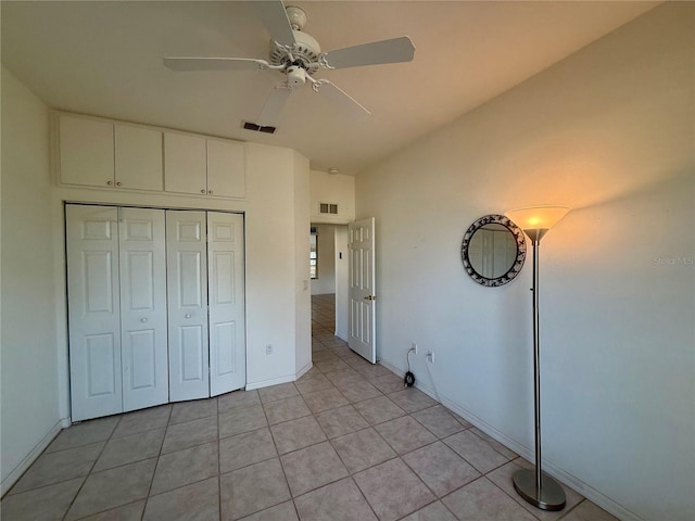 unfurnished bedroom with light tile patterned floors, a closet, visible vents, a ceiling fan, and baseboards