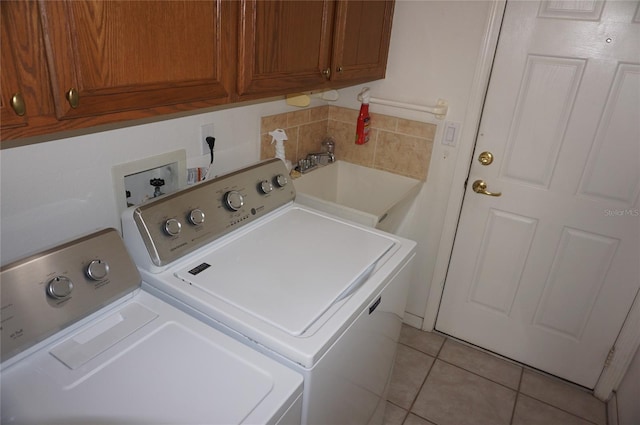 clothes washing area with cabinet space, independent washer and dryer, a sink, and light tile patterned floors