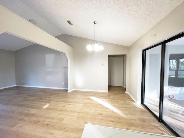 unfurnished dining area featuring vaulted ceiling, plenty of natural light, a textured ceiling, and a notable chandelier