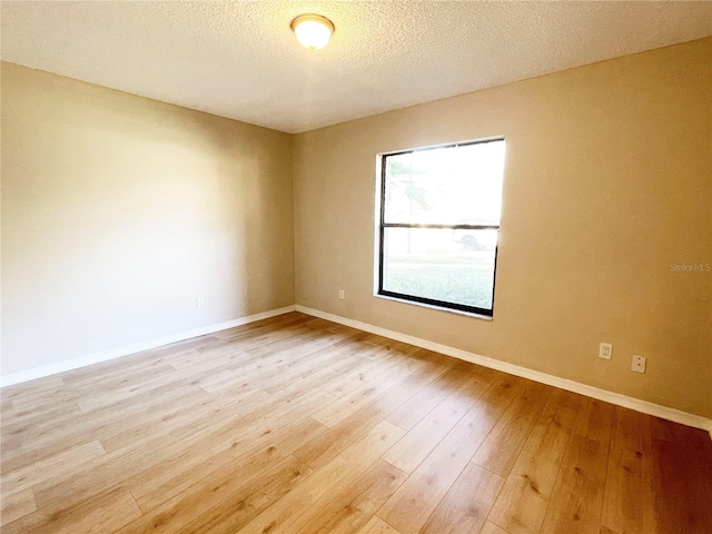 unfurnished room with light hardwood / wood-style flooring and a textured ceiling