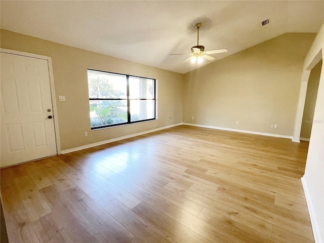 empty room featuring ceiling fan, light wood-type flooring, and vaulted ceiling