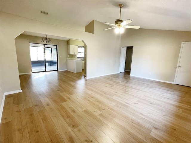 unfurnished living room featuring ceiling fan with notable chandelier, light wood-type flooring, and vaulted ceiling