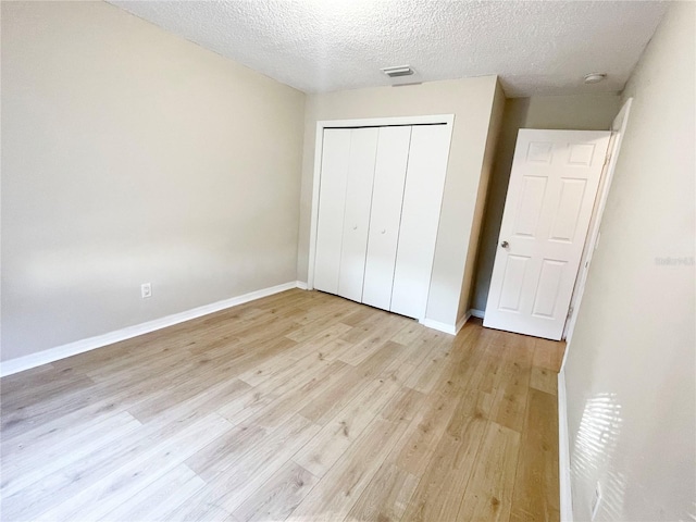 unfurnished bedroom featuring a closet, a textured ceiling, and light wood-type flooring