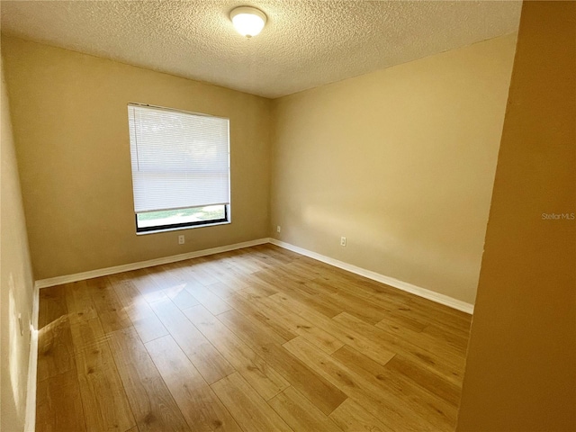 spare room with a textured ceiling and light hardwood / wood-style flooring