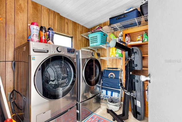 laundry room featuring wood walls and separate washer and dryer