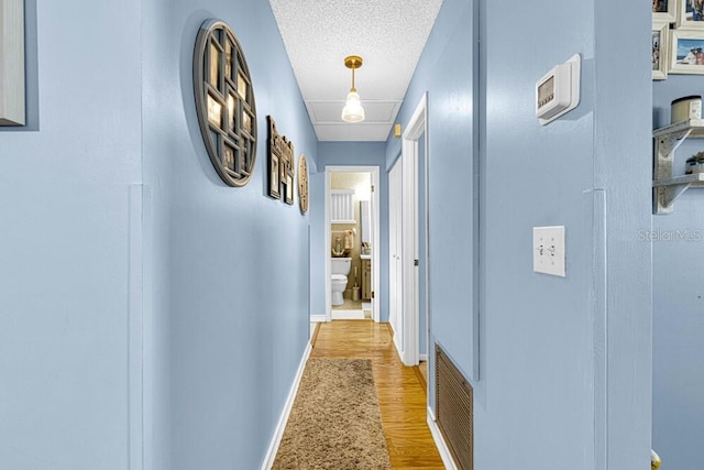 hallway featuring a textured ceiling and light wood-type flooring