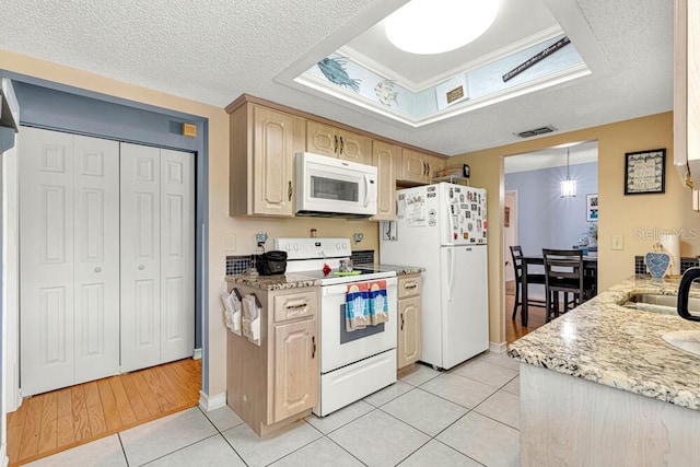 kitchen featuring light wood-type flooring, white appliances, a textured ceiling, and light brown cabinetry