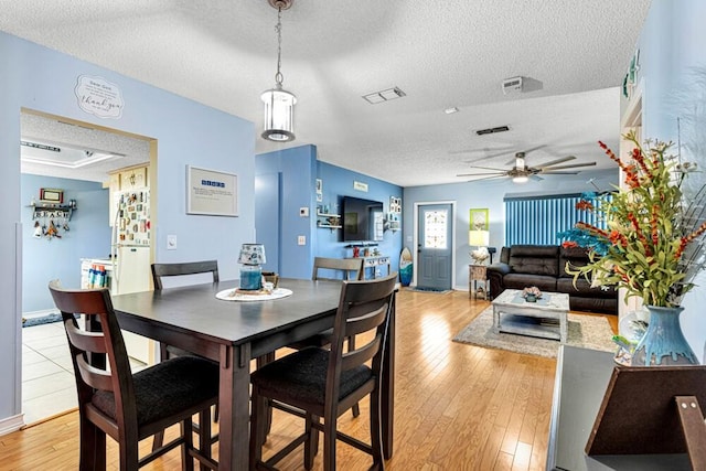 dining space featuring ceiling fan, light hardwood / wood-style floors, and a textured ceiling