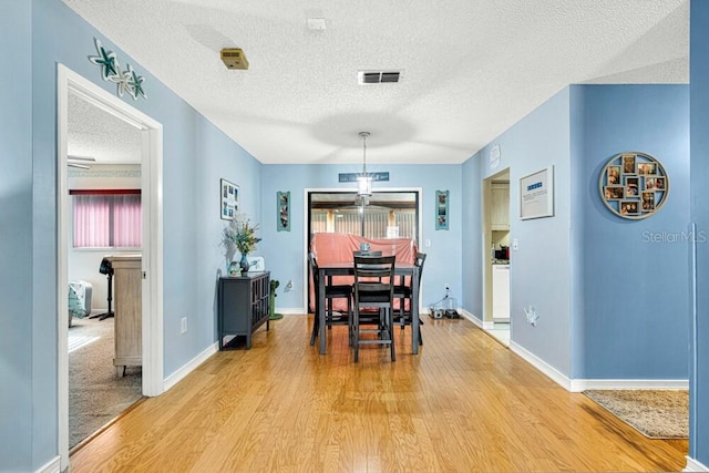 dining space with a textured ceiling and hardwood / wood-style flooring