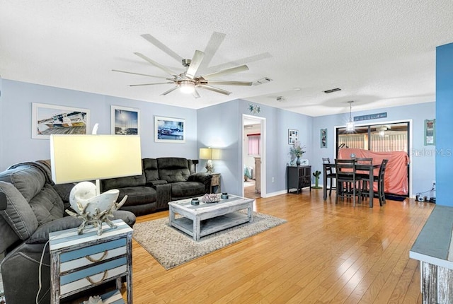 living room with ceiling fan, wood-type flooring, and a textured ceiling