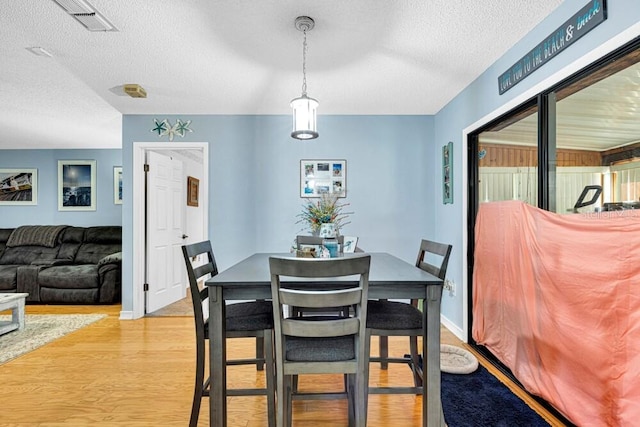 dining room with light hardwood / wood-style floors and a textured ceiling