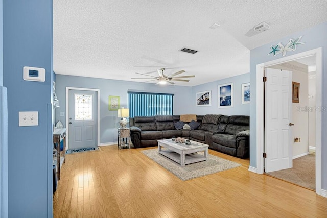 living room with ceiling fan, a textured ceiling, and hardwood / wood-style flooring