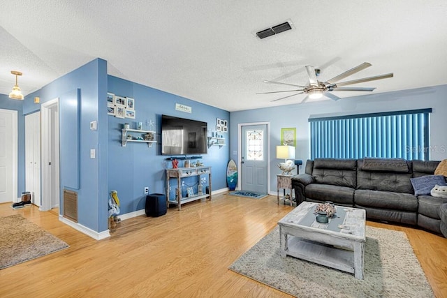 living room with hardwood / wood-style floors, ceiling fan, and a textured ceiling