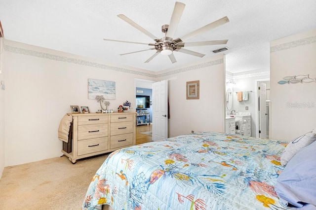 carpeted bedroom featuring a textured ceiling, ensuite bath, and ceiling fan