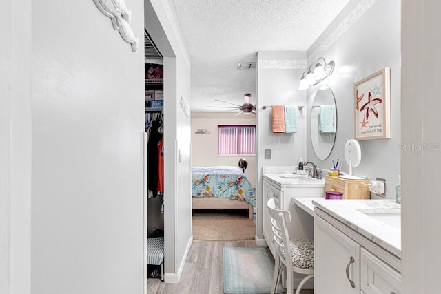 bathroom featuring vanity, wood-type flooring, a textured ceiling, and ceiling fan