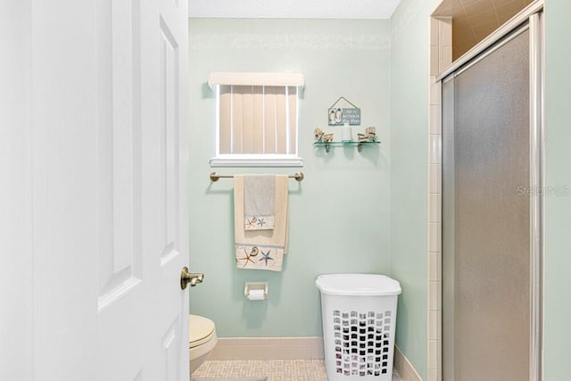 bathroom with tile patterned floors, toilet, and a shower with door