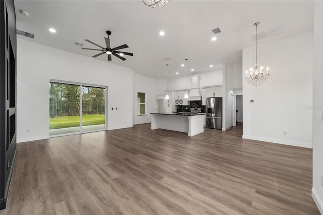 unfurnished living room featuring ceiling fan with notable chandelier and light hardwood / wood-style floors