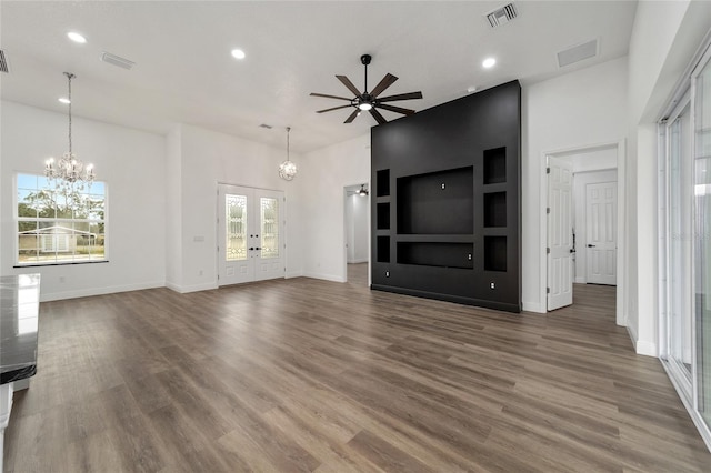 unfurnished living room featuring french doors, plenty of natural light, ceiling fan with notable chandelier, and hardwood / wood-style flooring