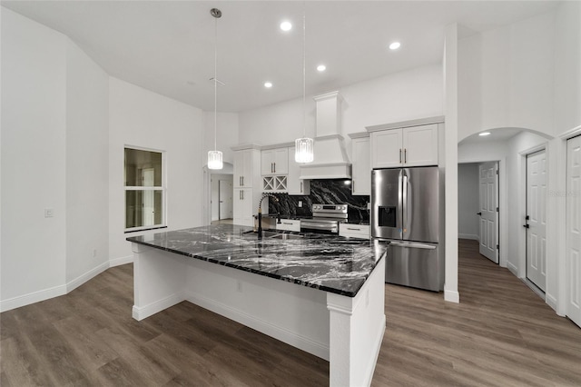 kitchen featuring premium range hood, white cabinetry, decorative light fixtures, and appliances with stainless steel finishes