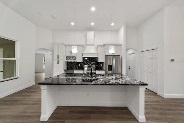 kitchen featuring white cabinets, stainless steel fridge with ice dispenser, decorative light fixtures, and a breakfast bar area