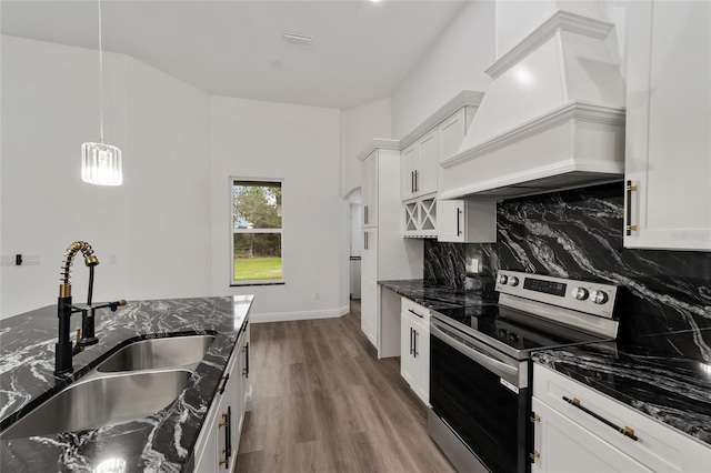 kitchen featuring white cabinets, electric range, premium range hood, and dark stone countertops