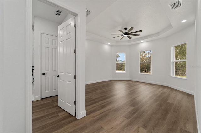 unfurnished room with dark hardwood / wood-style floors, ceiling fan, and a tray ceiling