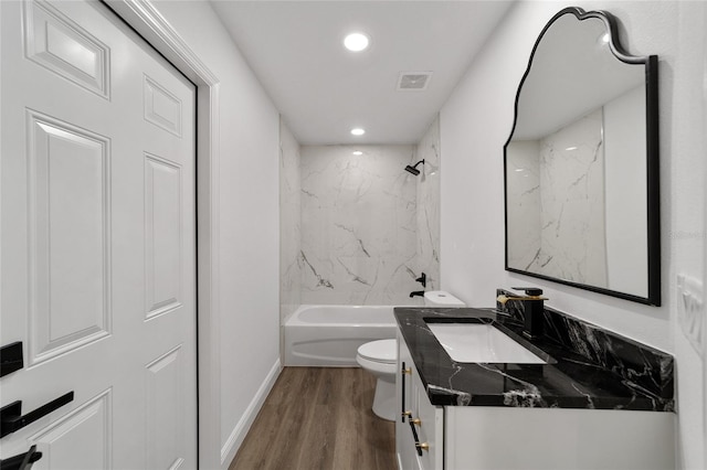 full bathroom featuring hardwood / wood-style floors, vanity, toilet, and tiled shower / bath