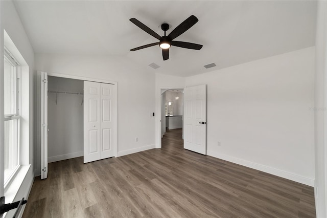 unfurnished bedroom featuring wood-type flooring, a closet, ceiling fan, and lofted ceiling