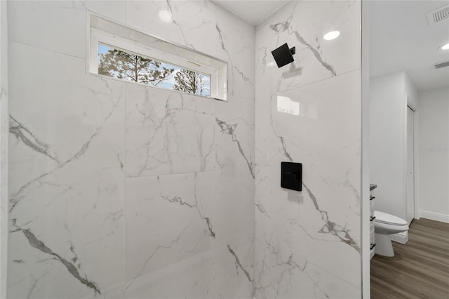 bathroom featuring a tile shower and toilet